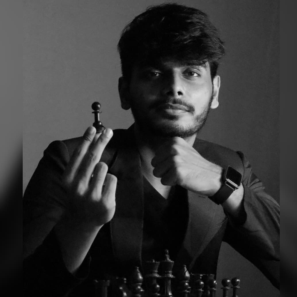 GM Akash Ganesan holding a chess pawn